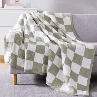 A green and white checkered throw blanket draped across an armchair