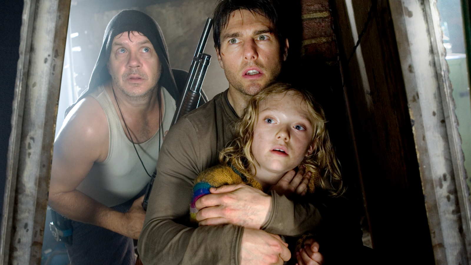 Still from the sci-fi movie "World of the Worlds" (2005). Hiding in a basement is a man holding a gun and another man hugging his young daughter. They are all very scared.