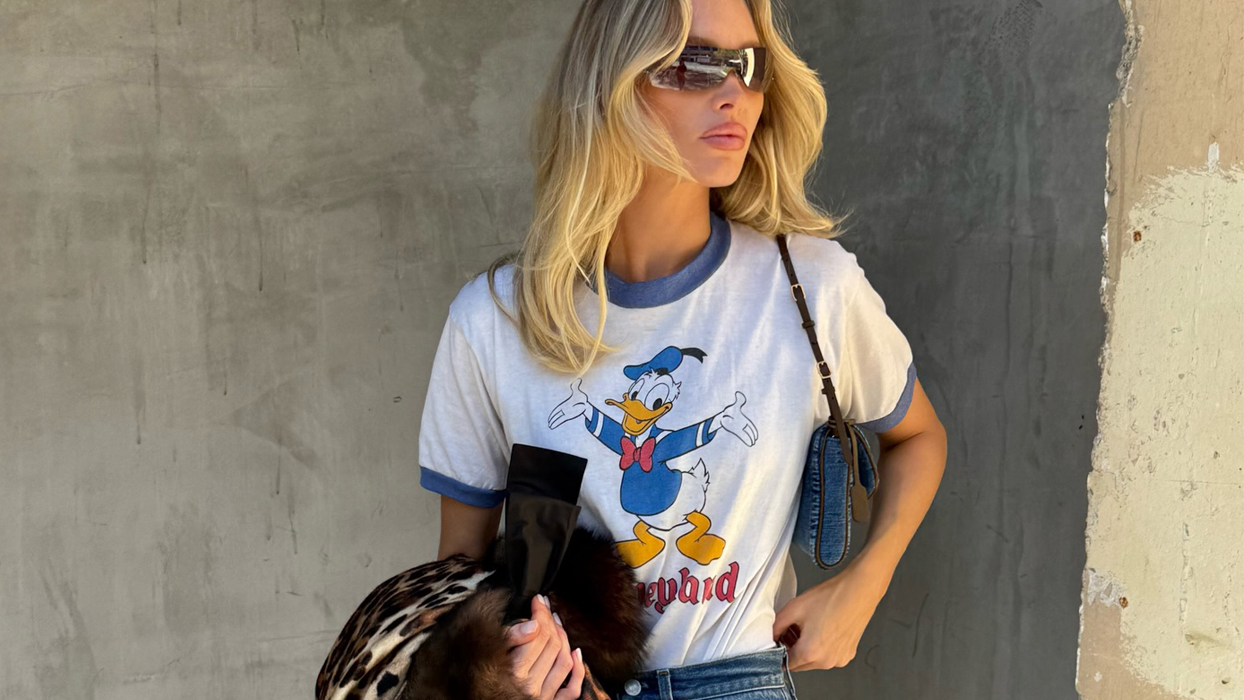 Elsa Hosk wearing a Disney T-shirt, Valentino leopard-print coat, bootcut jeans, and brown kitten heels from The Row.