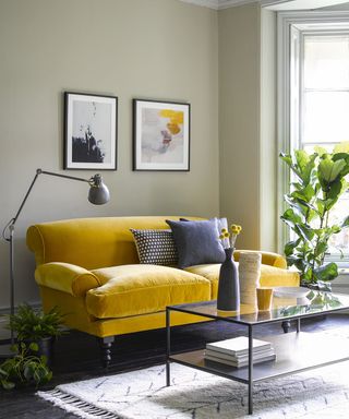 Beige living room with yellow sofa and prints on wall