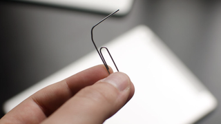 A person holding a paperclip, which is essential for sim card removal