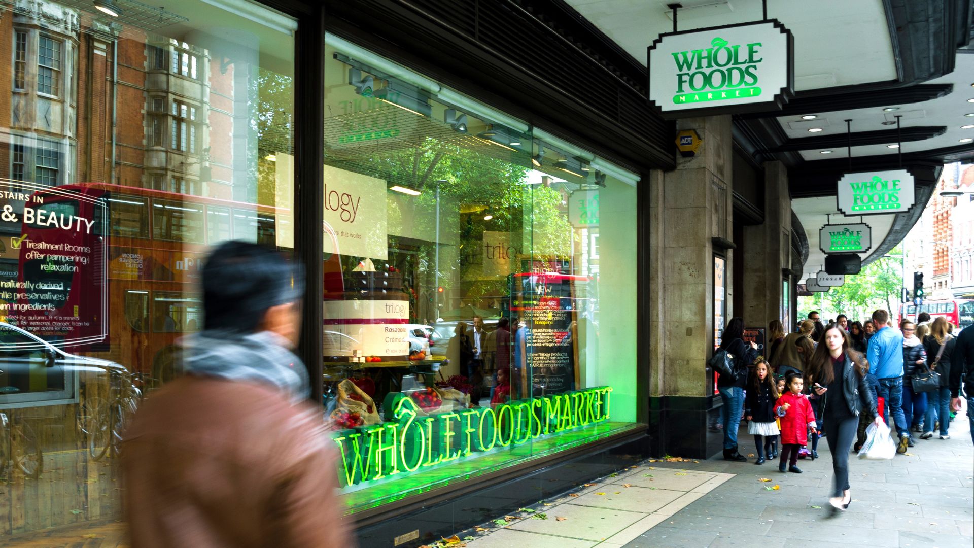 Whole Foods Market in London with people in front of the entrance and on the sidewalk.