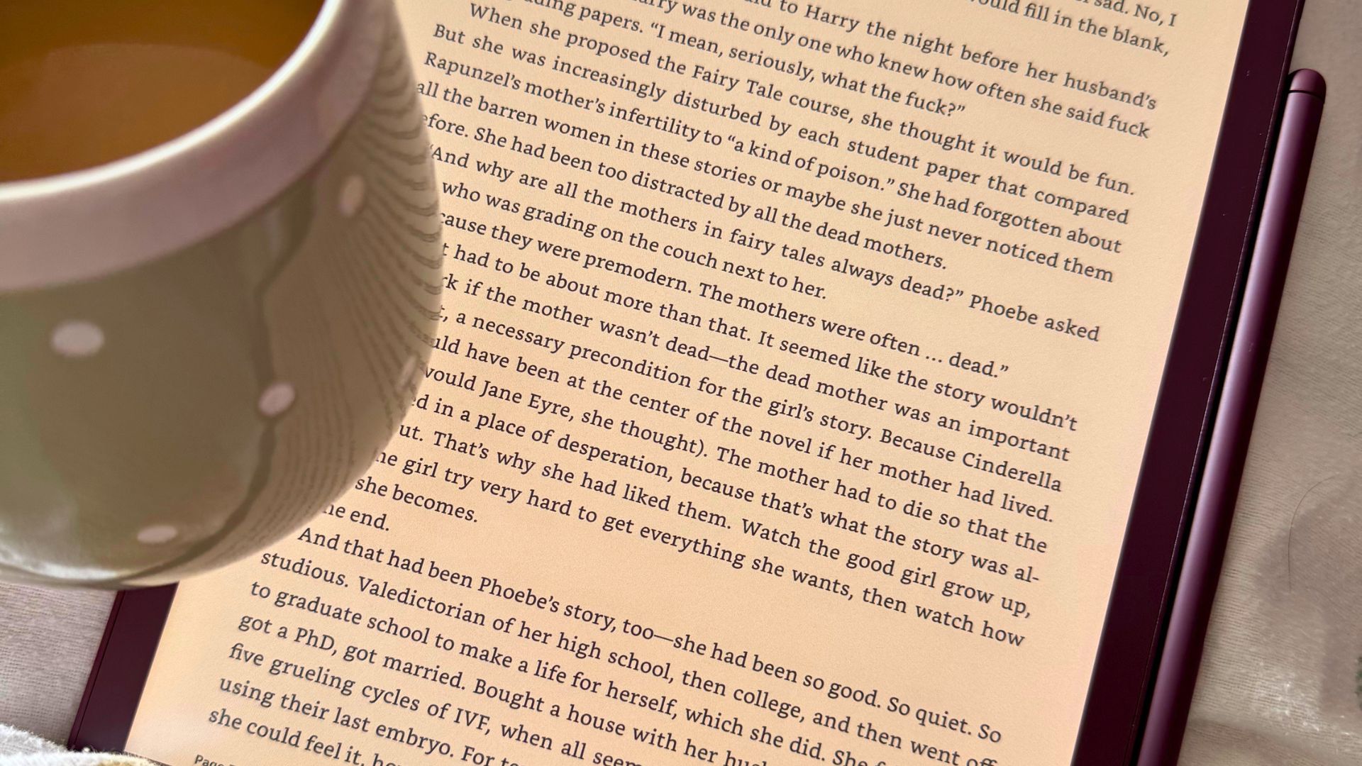 The Amazon Kindle Scribe Colorsoft pictured while the tester holds a cup of coffee and reads in bed