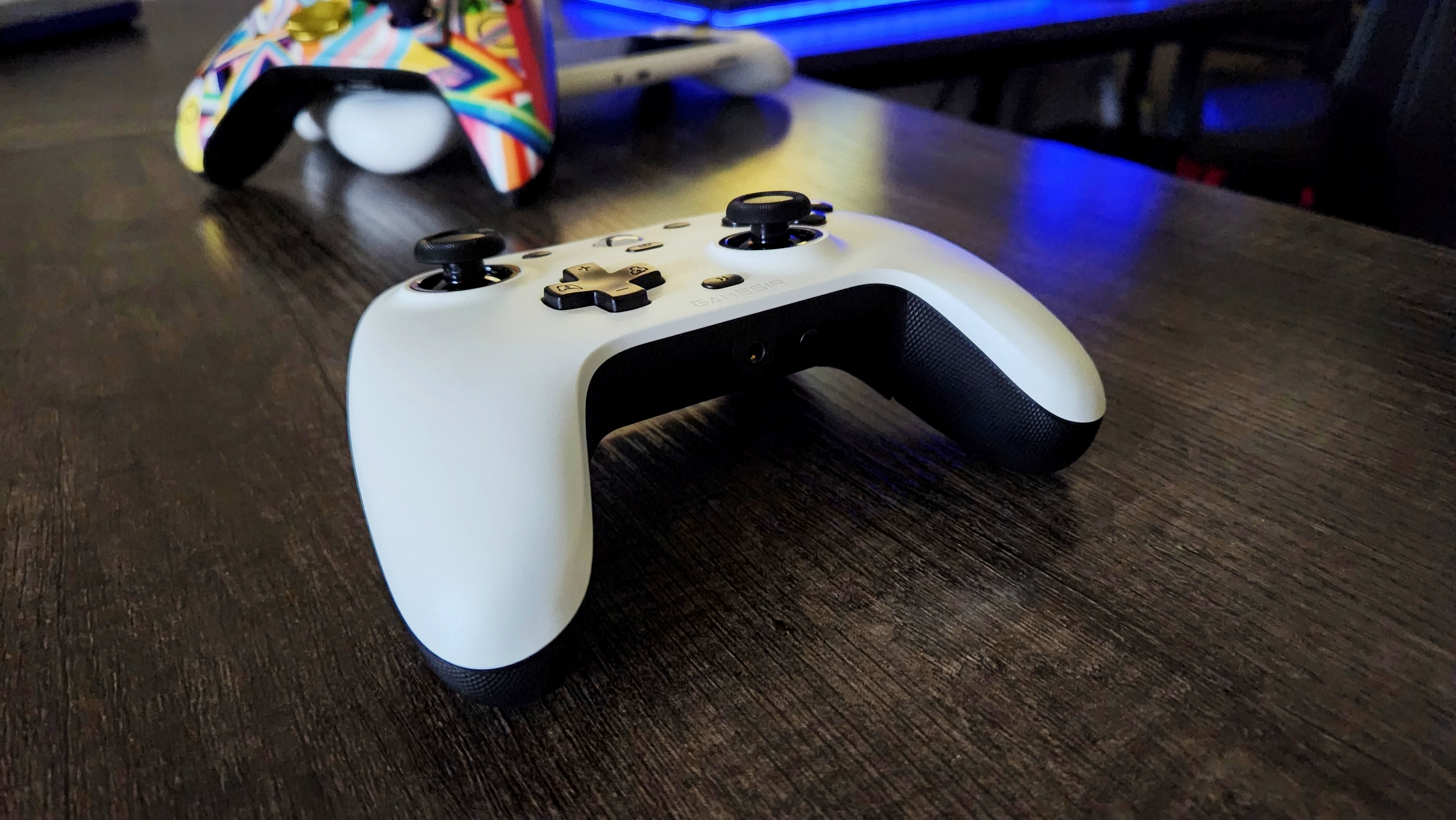 GameSir G7 Wired Controller, in white, laying on desk with Logitech G Cloud and Xbox Wireless Controller in background.