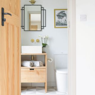 White bathroom with wooden door and sink cabinet with gold accents