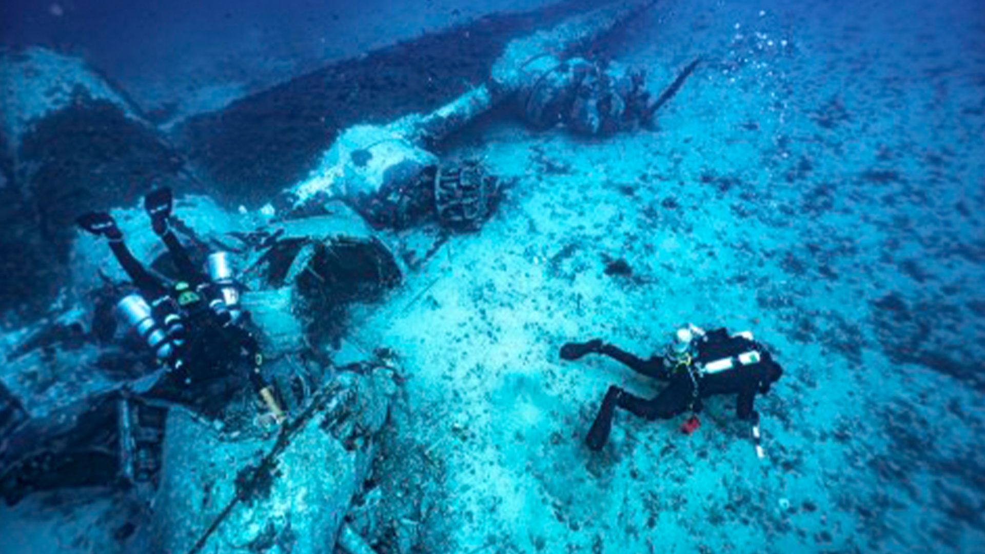 Two divers examine the wreck under water.