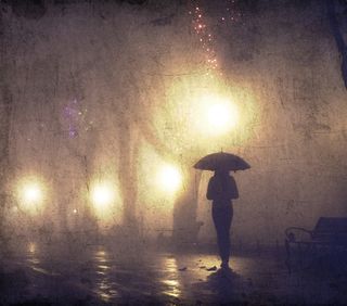 A woman stands alone on the street during a rainy night