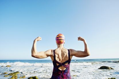 Woman in swimwear flexing her muscles on a beach