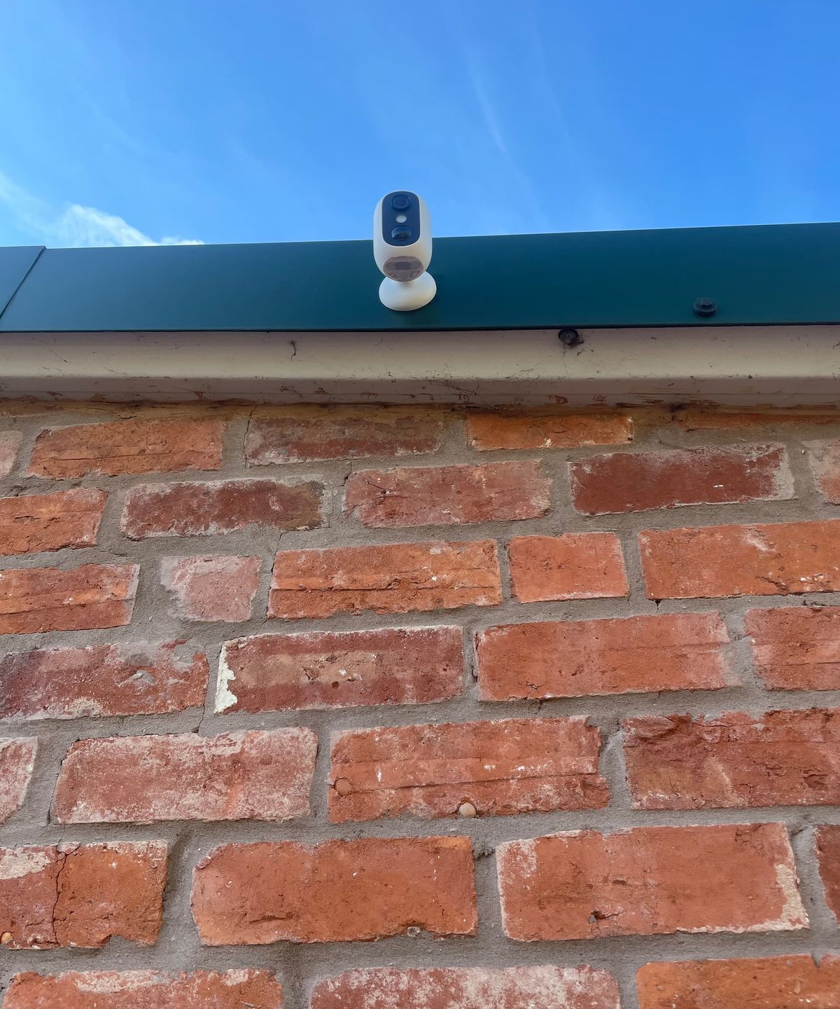 A eufy C35 camera on a roof ledge of a brick house