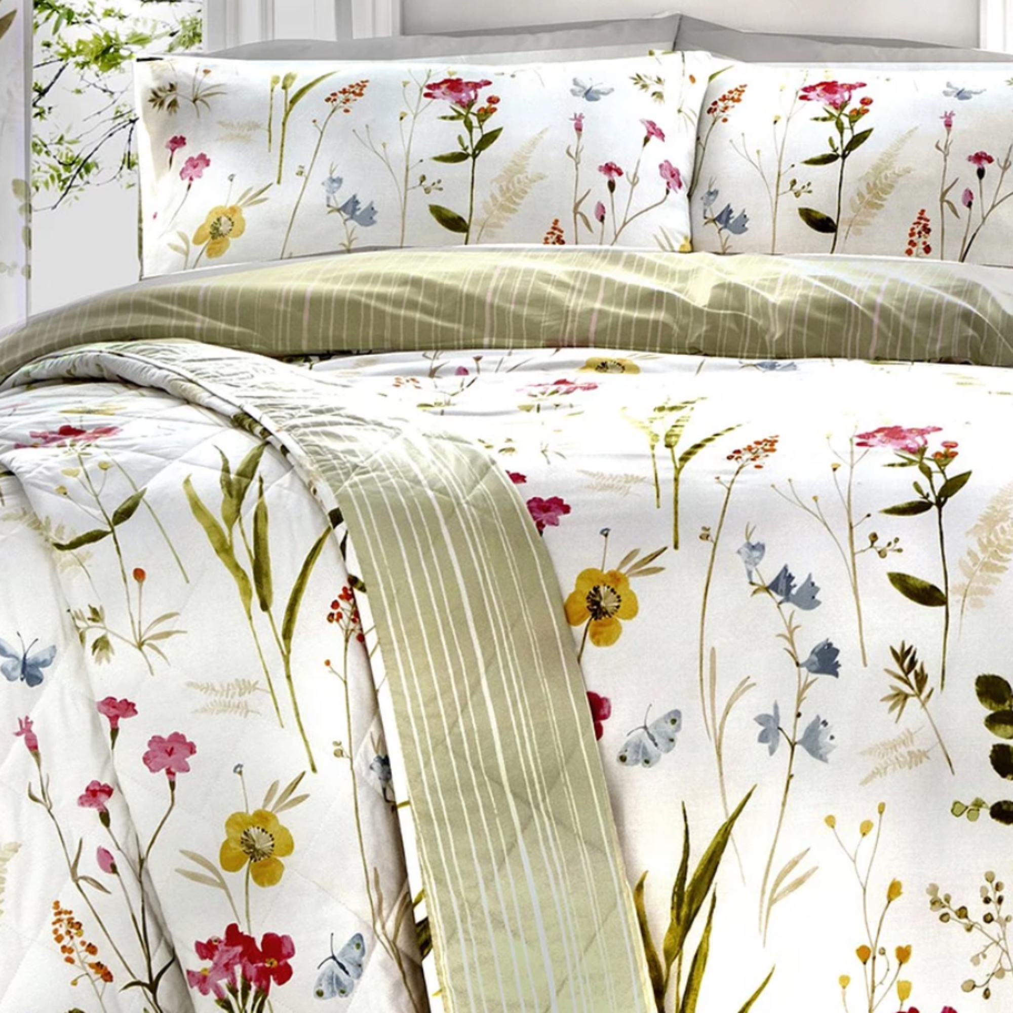 White and green bedding with wildflower pattern styled in a white bedroom