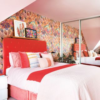 Pink bedroom with floral wallpaper, upholstered velvet headboard, mirrored built-in wardrobes