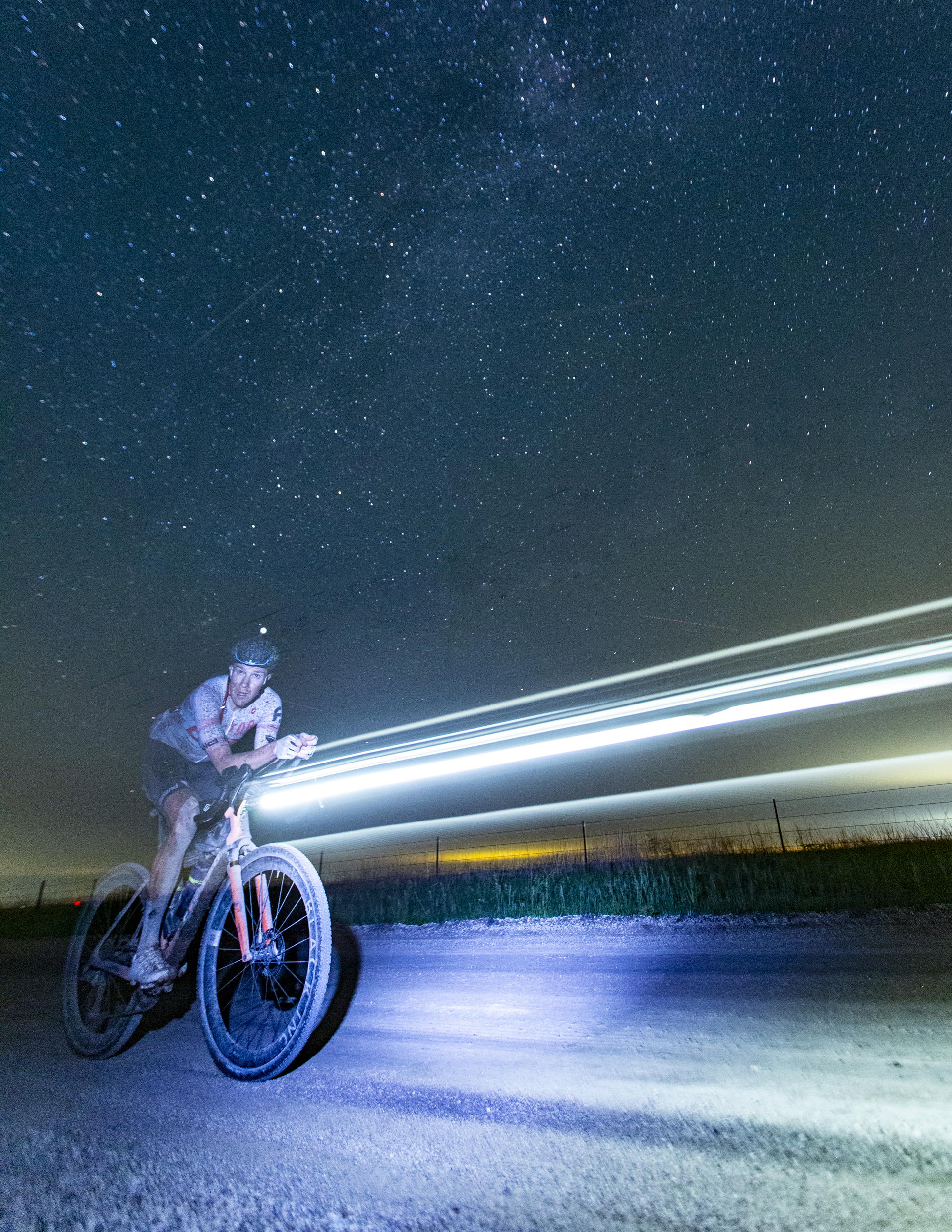 Rob Britton looks over at a tripod as his winning ride at Unbound Gravel XL is captured on camera with the multitude of stars shining down on the Flint Hills of Kansas