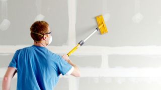 Man using pole sander on plasterboard wall