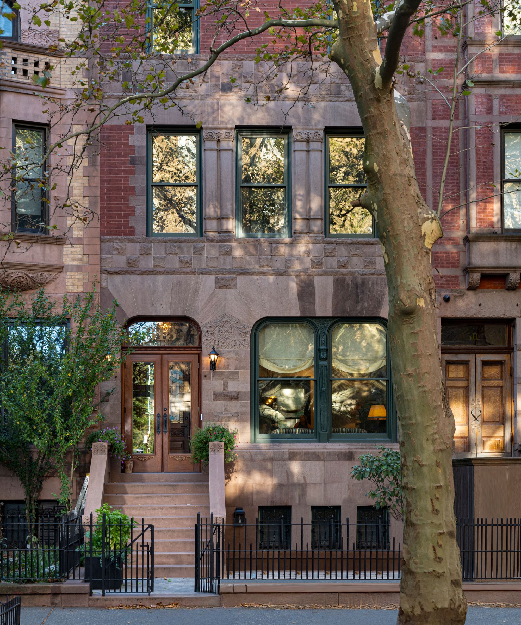 a traditional Hamilton Heights five story brownstone with a large tree set outside the steps