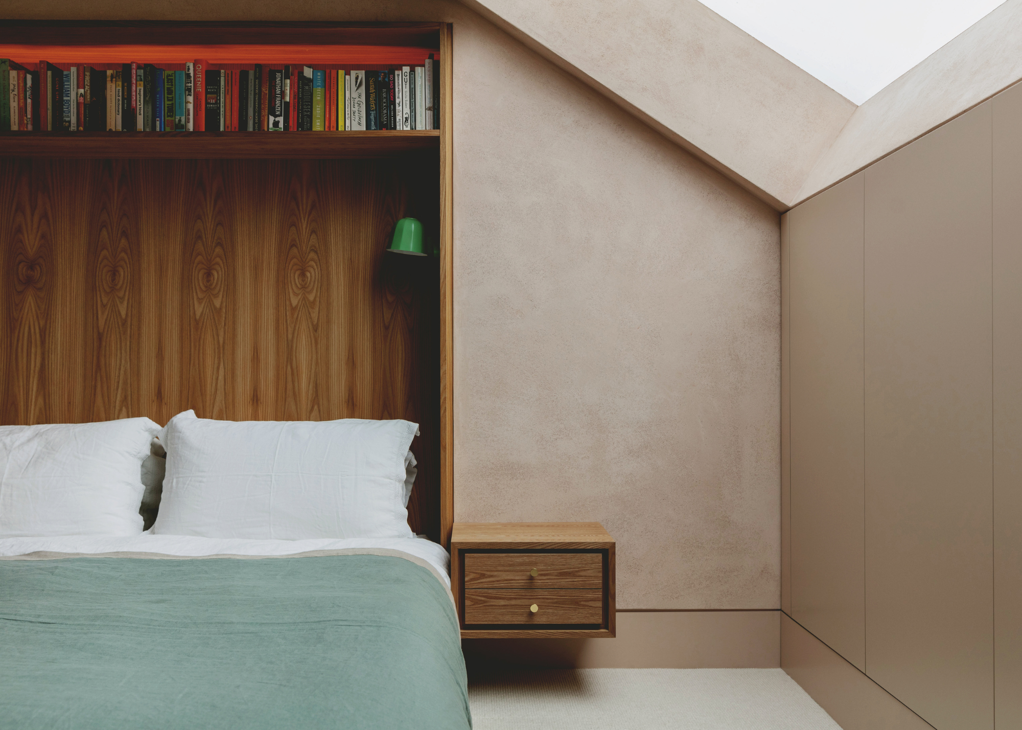 wooden custom built bed with a book shelf, attached bedside table and lights