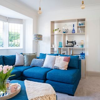 neutral living room with blue corner sofa and shelf unit