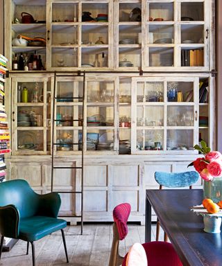 kitchen with large distressed glazed cabinet and ladder, metal table and colorful chairs