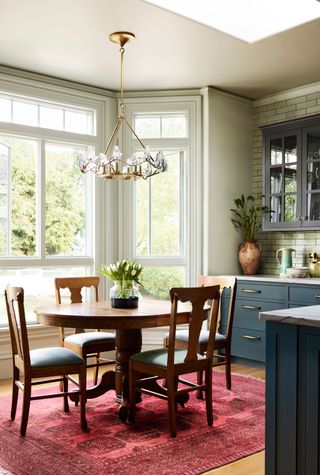 round breakfast table in window of kitchen with blue cabinets