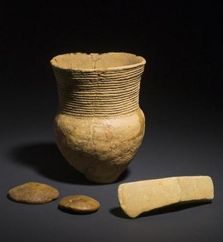 A Corded Ware vessel, an axe and two discs made of amber from an early male grave.