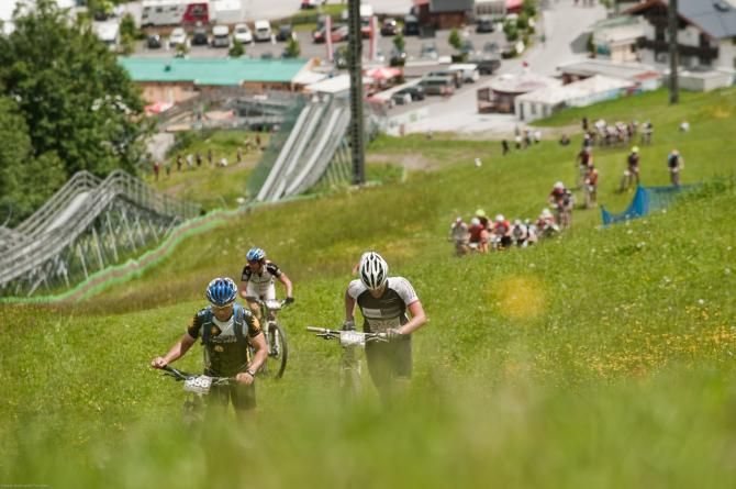 Riders walk up a steep ski slope during stage 3 of the Bike Four Peaks
