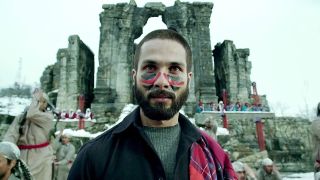 Shahid Kapoor with paint on his face outside of a castle like building in haider