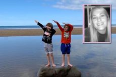 Two little boys on the beach gesturing with their arms