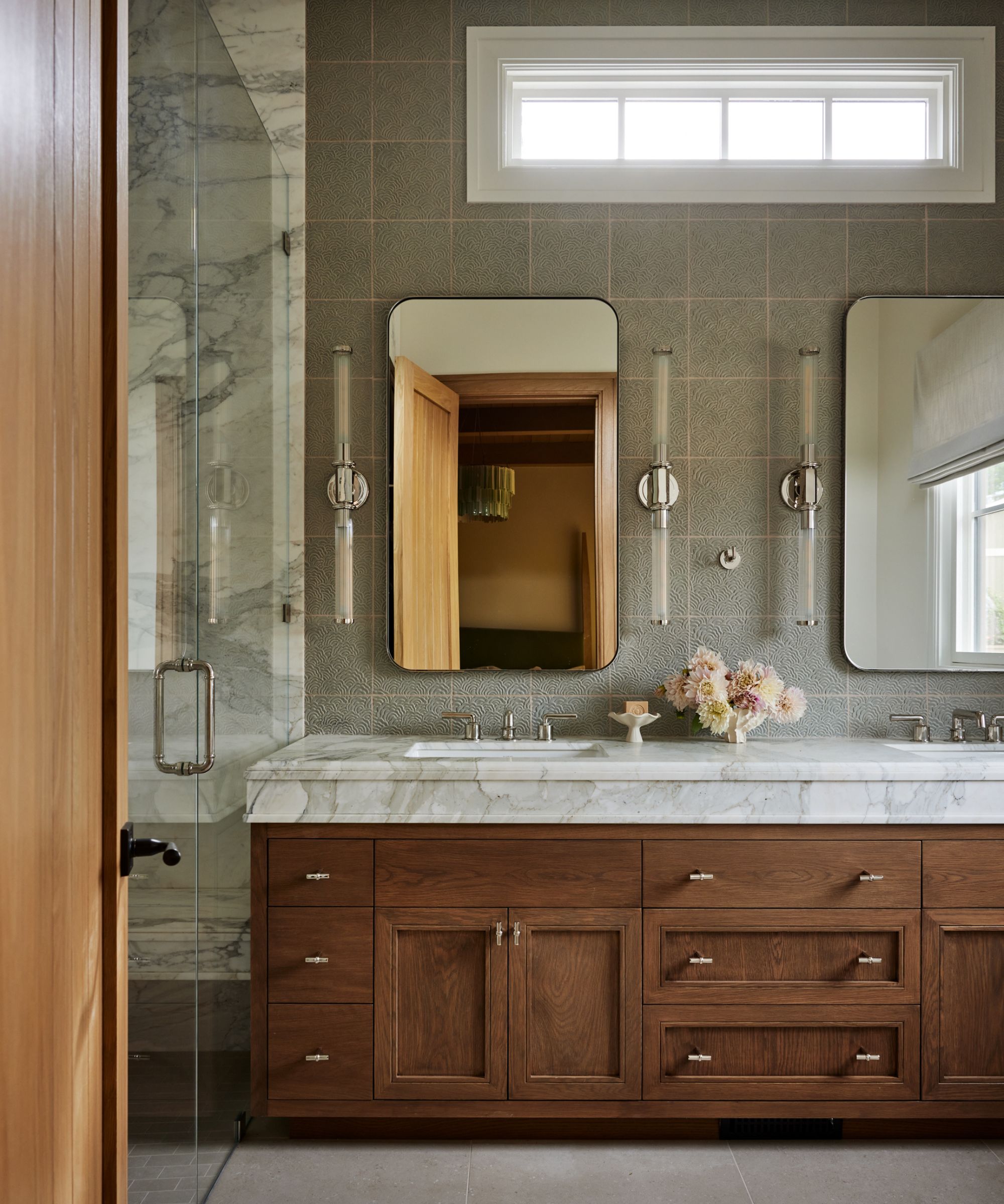 A bathroom with pale green wall tiles and a wooden vanity