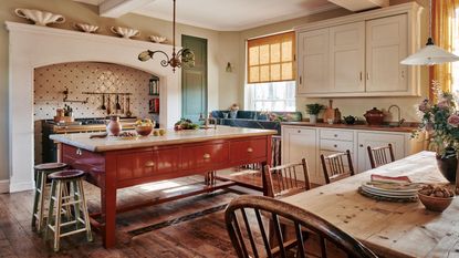 A traditional kitchen in a Victorian home with white cabinets and a terracotta red freestanding island