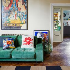 A magnolia-painted living room with a green velvet sofa and fun cushions