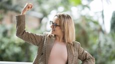 A professionally dressed woman flexes her bicep like she's in charge.