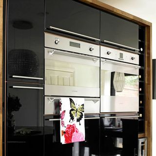 kitchen with tall black wall unit with microwave oven and tea towel