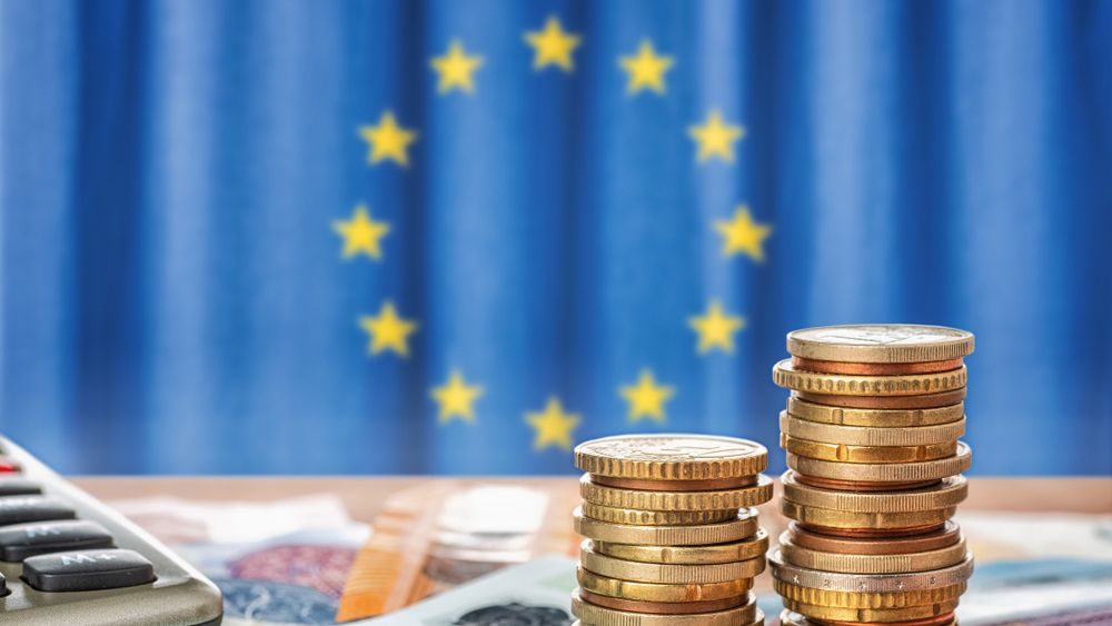 A pile of coins with EU flag in background