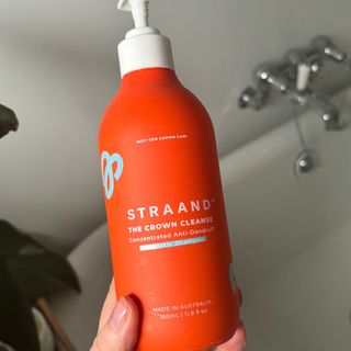 Laura holding STRAAND The Crown Cleanse Concentrated Anti-Dandruff Prebiotic Shampoo