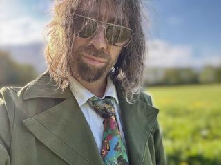 UK musician Mikee W. Goodman wearing the green jacket and necktie from RPG Disco Elysium.