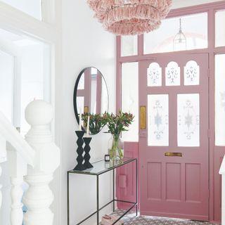 Hallway with grey and white tiled floor, white walls and pink light fitting and front door with patterned frosted glass panels