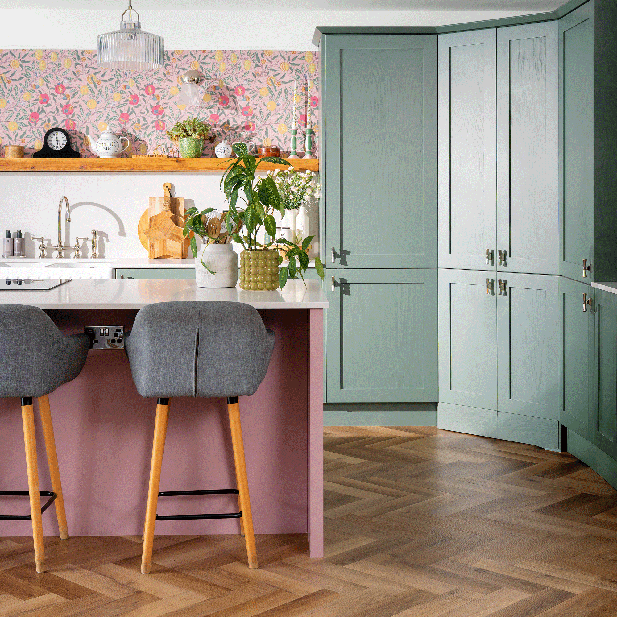 a pink and green kitchen with floor to ceiling green cabinets a pink kitchen island and pink patterned wallpaper
