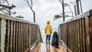 Boy and dog stood in rain