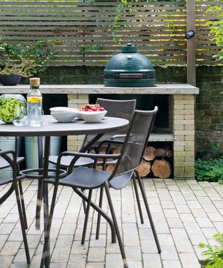 A metal table and chairs in front of a big green egg grill