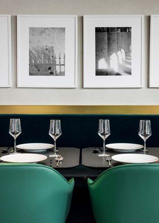 booths with short narrow tables and single seater chairs are backed by white framed photos lining the walls