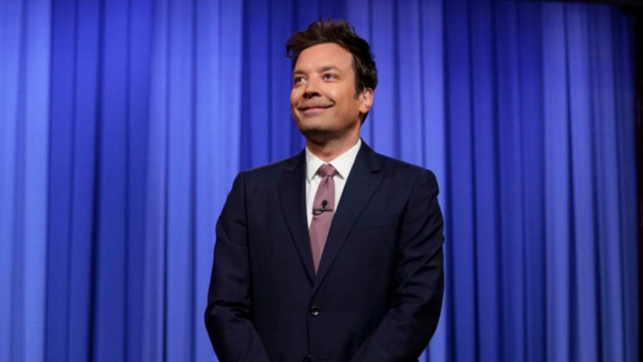 Jimmy Fallon in front of blue curtain on The Tonight Show
