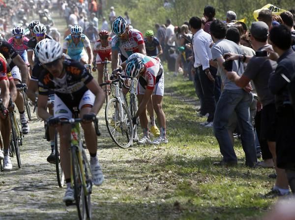 Punctures are commonplace in Paris-Roubaix, and a good teammate gives up his wheel to his captain.