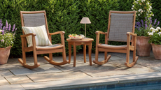 a patio with two rocking chairs and a table 