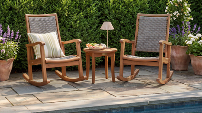 a patio with two rocking chairs and a table 