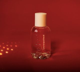Bel rebel's unrequited perfume in glass bottle against red background