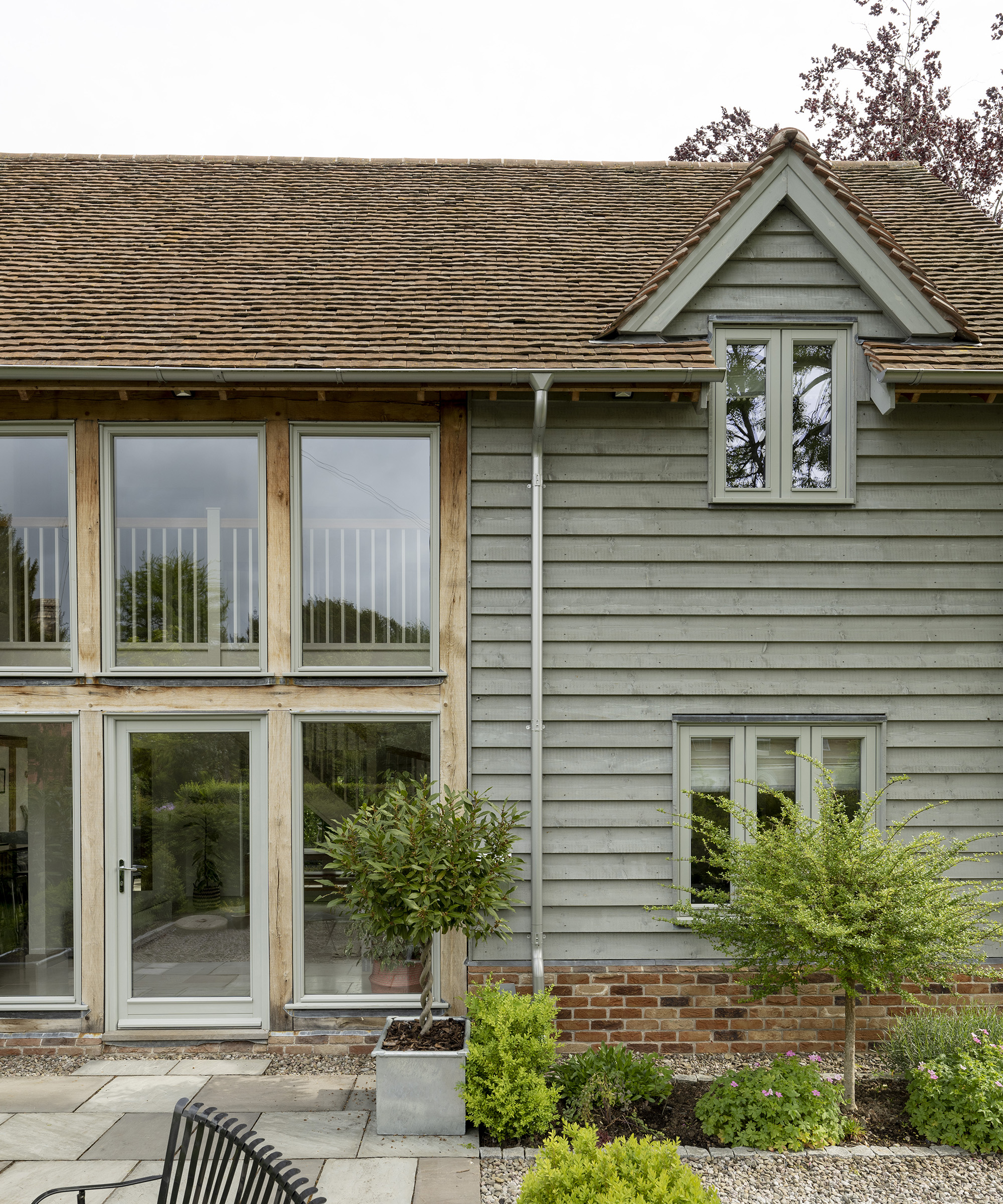 Exterior of a two storey oak frame house with brick and wood cladding and stone patio