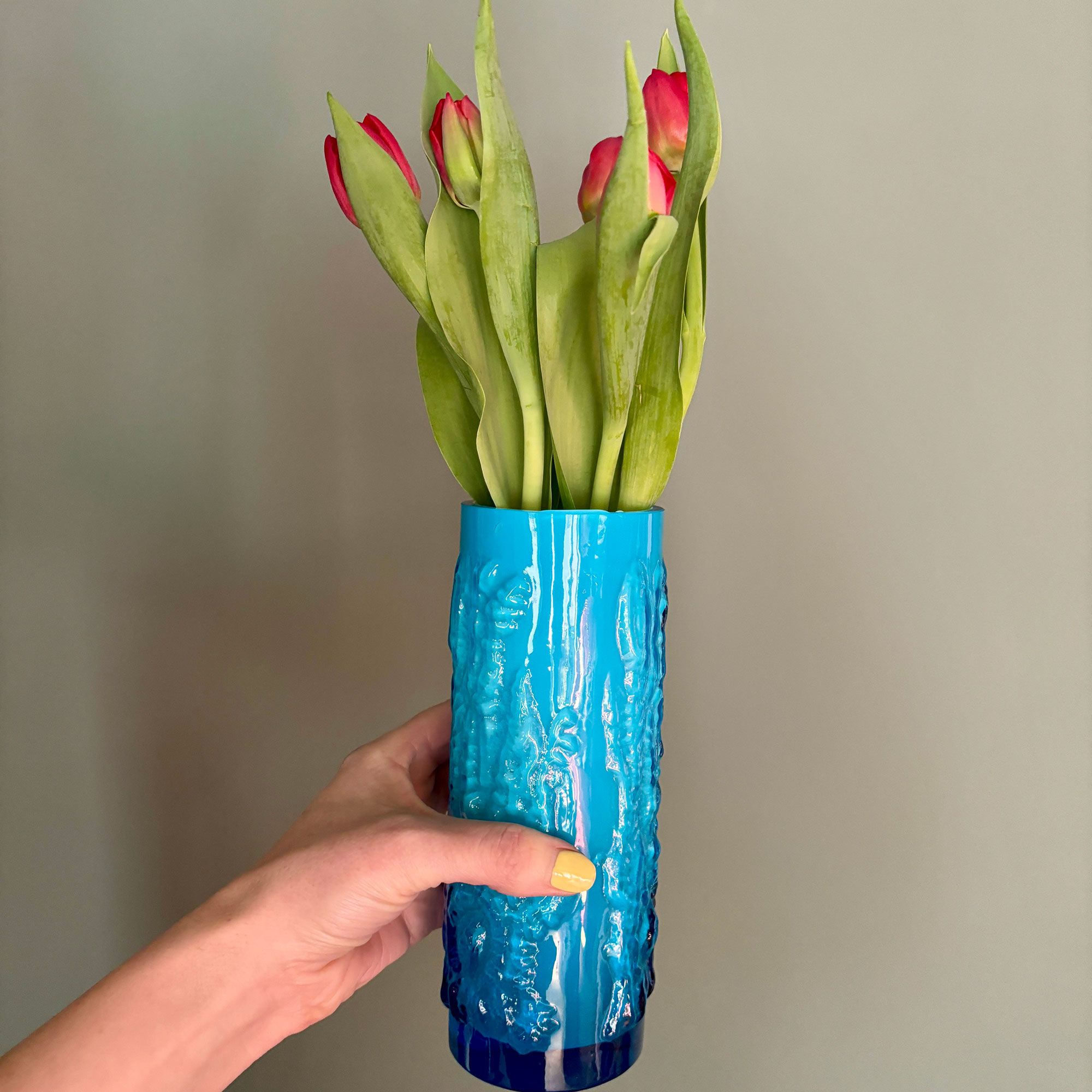 Woman holding blue glass vase filled with tulips