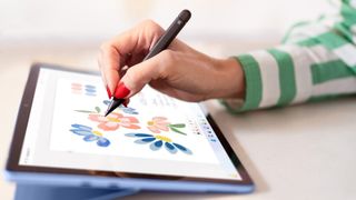 Surface Pro 9 auf einem Schreibtisch, auf dem jemand mit einem Stift Kunstwerke zeichnet