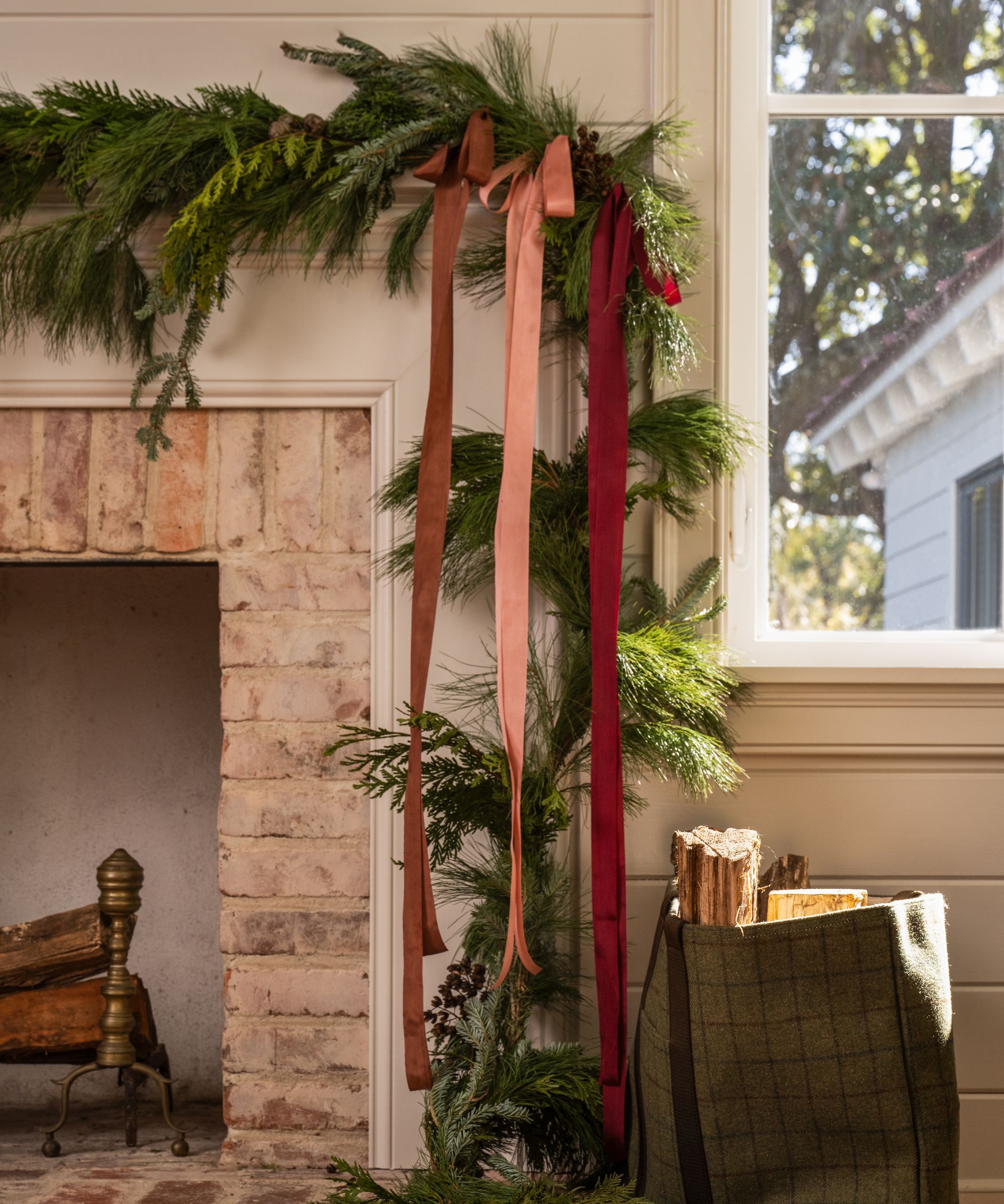 A fireplace with a Christmas garland and red and pink ribbon.