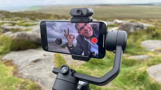 Zhiyun Smooth 5S AI gimbal held in a hand outside in a green field