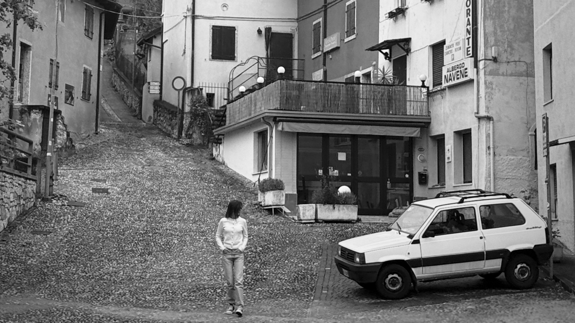 a person walking down a sloped cobblestone street 